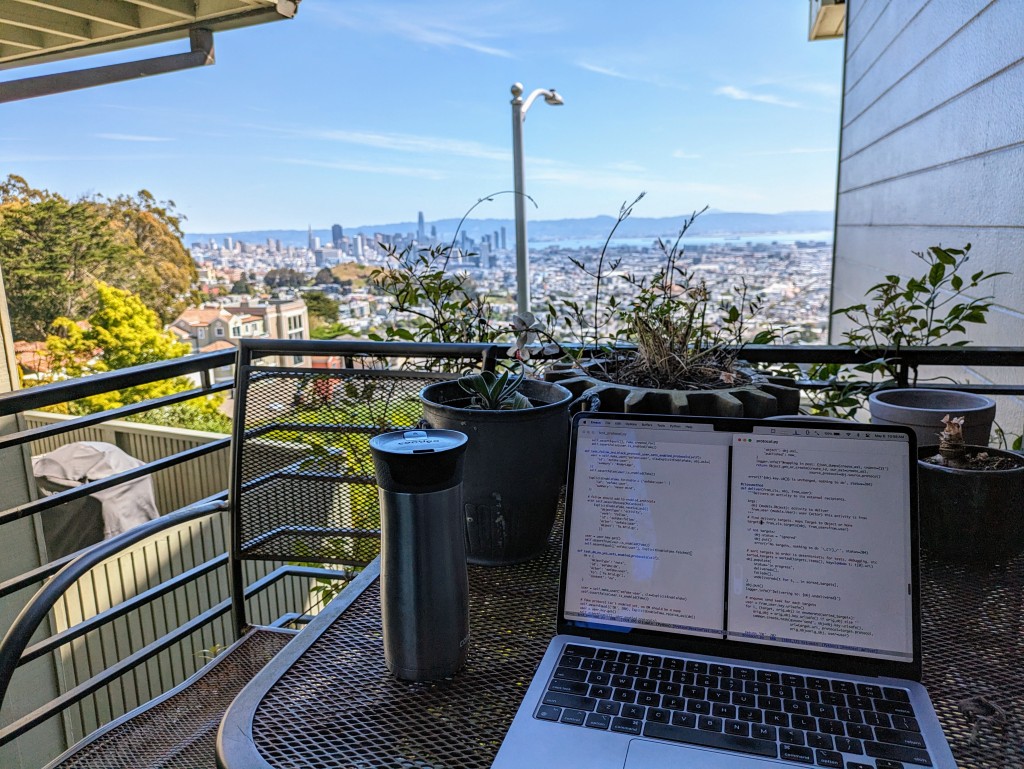 Balcony with laptop, coffee mug, plants, and view